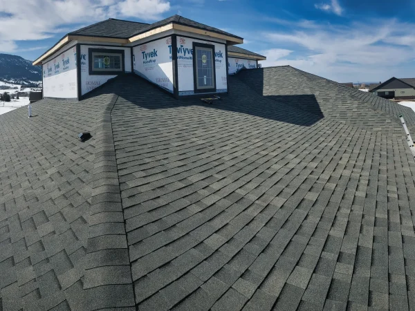 Architectural asphalt shingle installation on a complex gable roof for a new Missoula home.