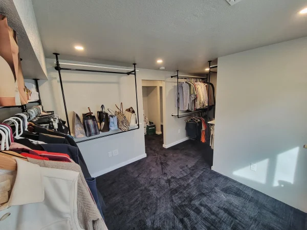 Finished walk-in closet featuring custom industrial pipe shelving in Missoula.