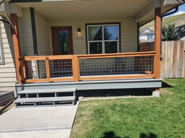 Custom wood porch railing with wire mesh panels and a matching gate in Missoula.