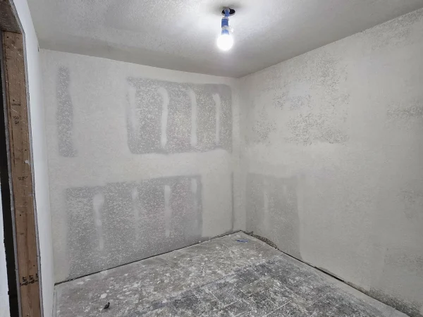 Drywall tape and mud applied to seams in a new interior room.