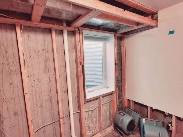Exposed framing around an egress window during a basement restoration in Missoula.