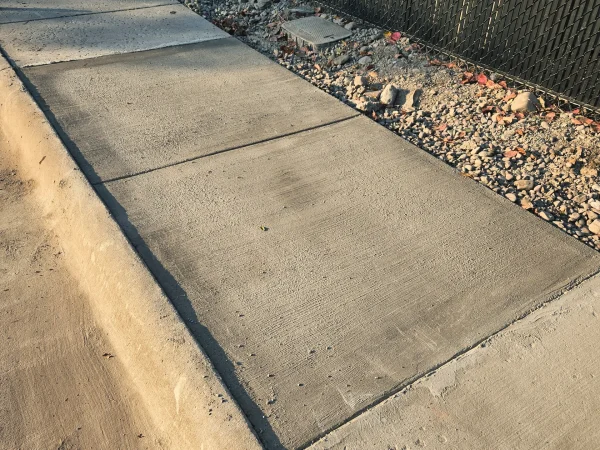 New concrete sidewalk section with a professional broom finish and integrated curb.