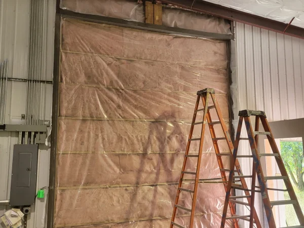Garage door enclosure with fiberglass insulation and vapor barrier in Missoula.