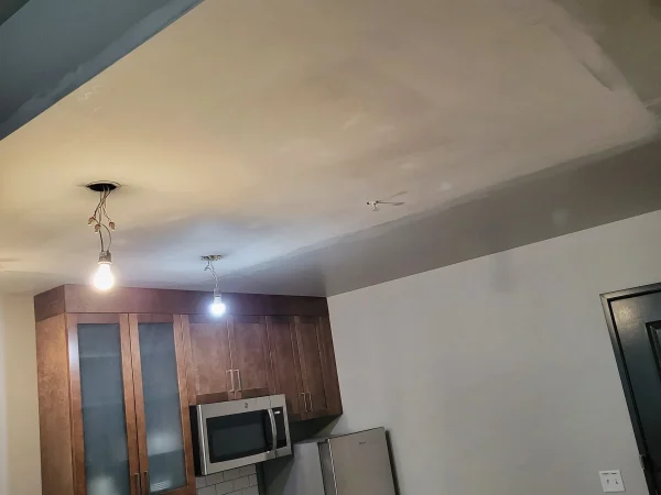 Smooth mudded ceiling over a hotel kitchenette area with bare lightbulbs hanging