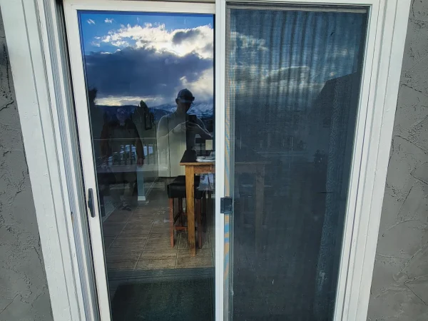 Exterior view of an old sliding glass patio door before removal