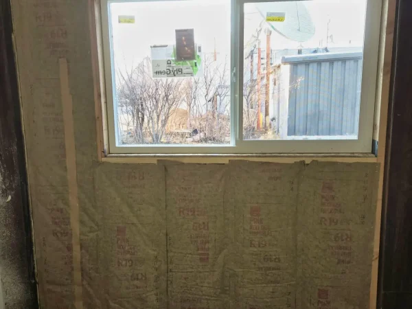 R-19 fiberglass insulation installed around a new window frame.