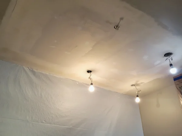 Room prepped with plastic drop cloths and newly taped and mudded ceiling