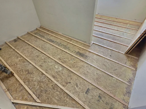 Custom wood sleepers installed over an OSB subfloor to correct a 2-inch deflection.